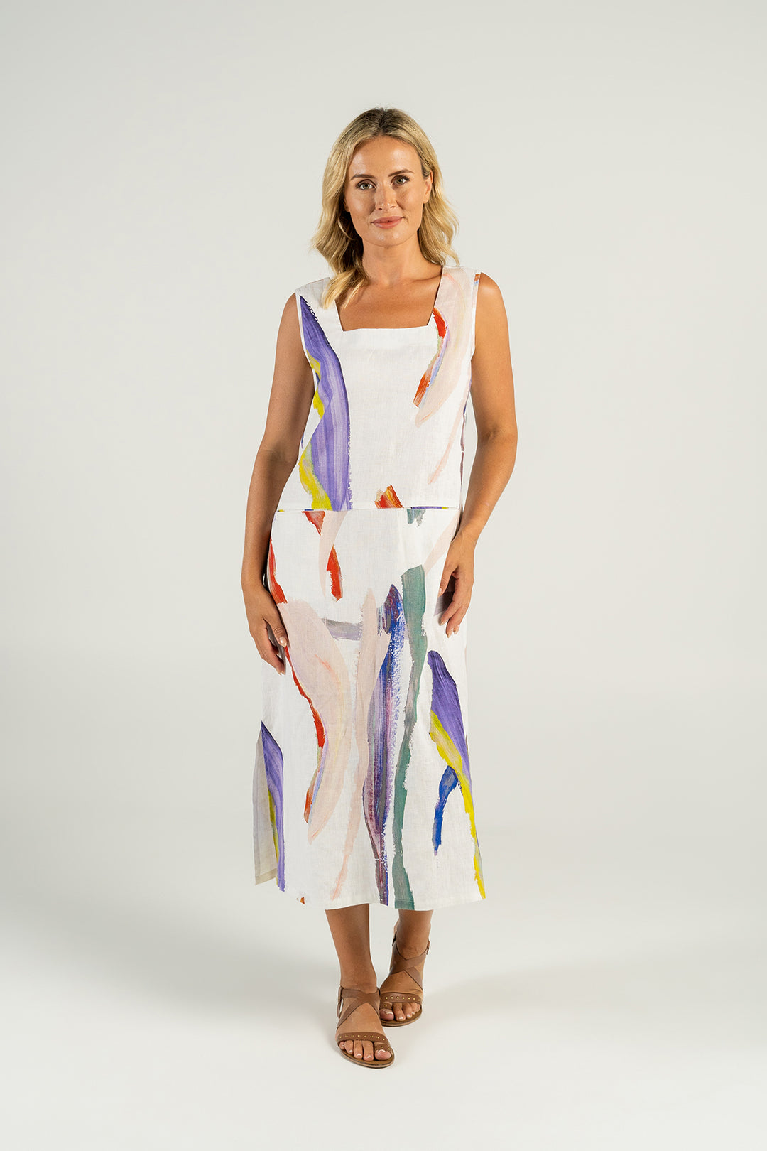 Woman wearing a white linen dress with splashes of colour front view from Pizazz Boutique Nelson Bay Dress Shop