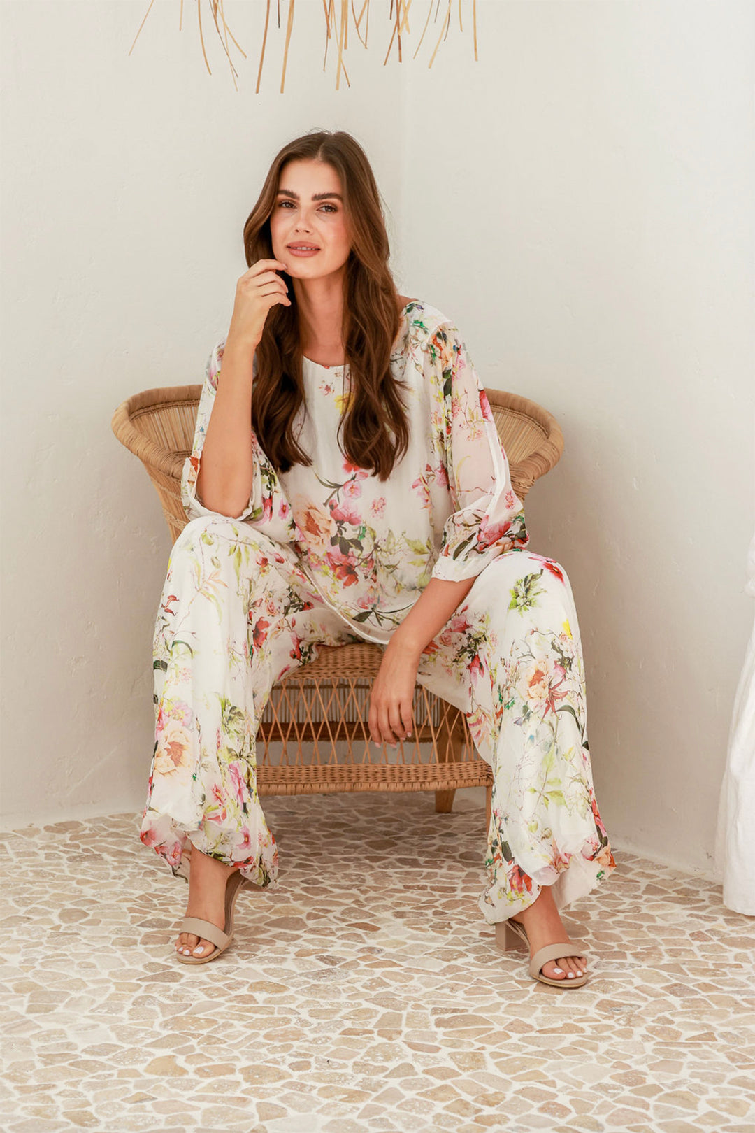 Woman wearing a floral top and pant set by The Italian Cartel, sold and shipped from Pizazz Boutique online women's clothes shops Australia seated view