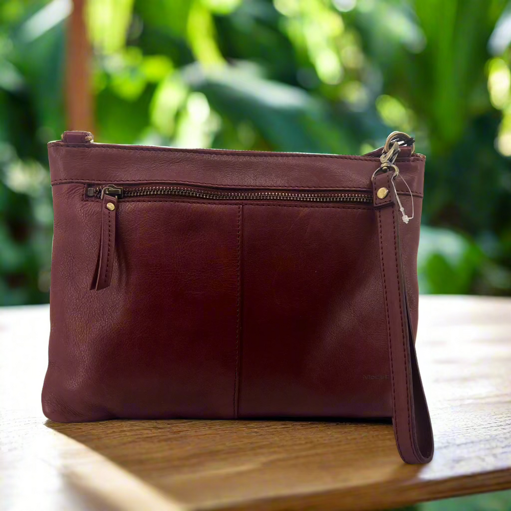 red crossbody handbag sitting on wooden table. 