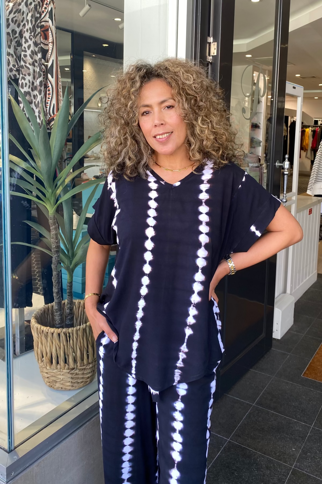 Woman in a tie-dye outfit standing in front of a store entrance