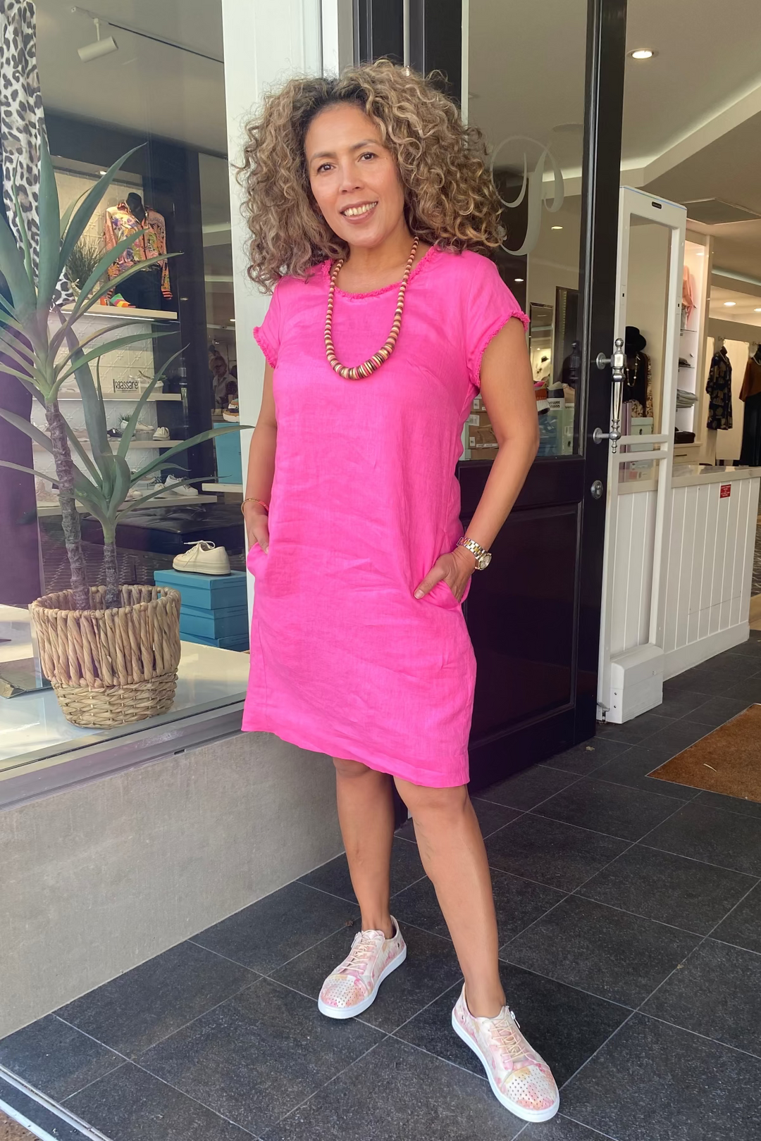 Woman in a pink dress standing outside a store
