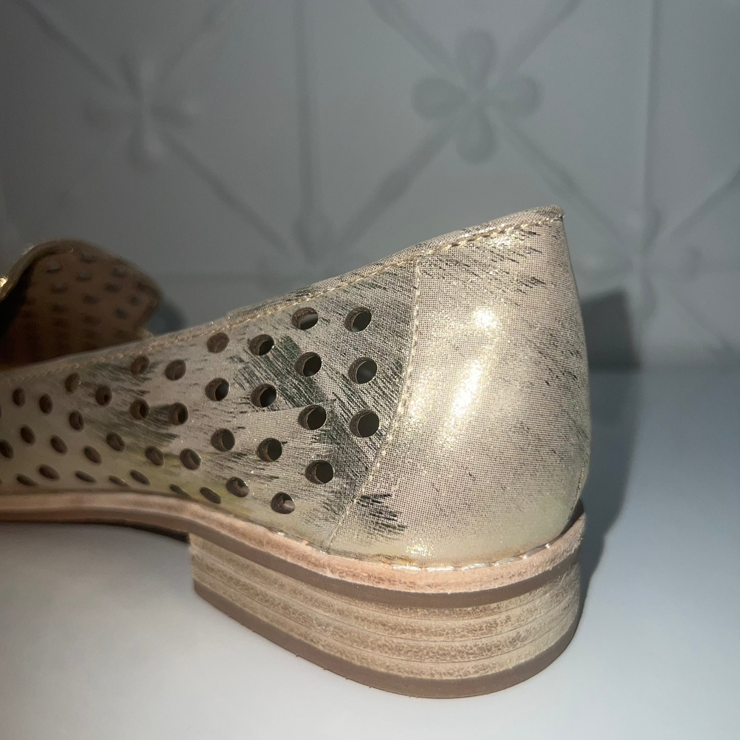 Metallic shoe with perforated design on a white surface