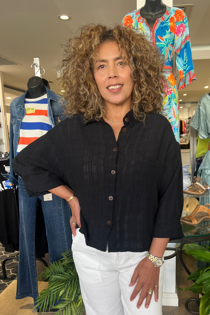 Woman standing in a clothing store with mannequins and clothing in the background