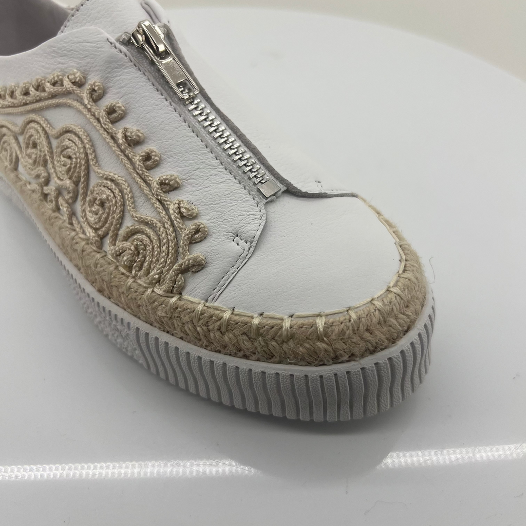 White sneaker with decorative pattern and zipper on a white background