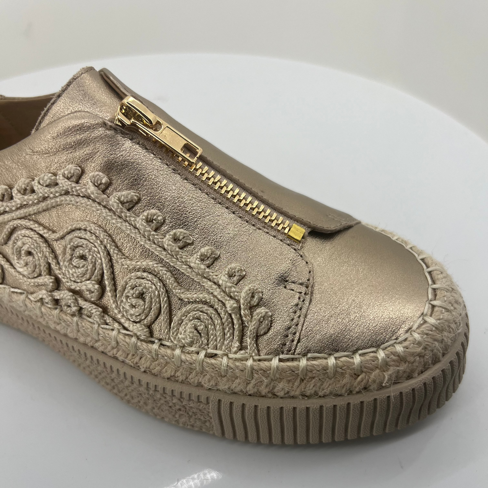 Metallic sneaker with decorative patterns and a gold zipper on a white background