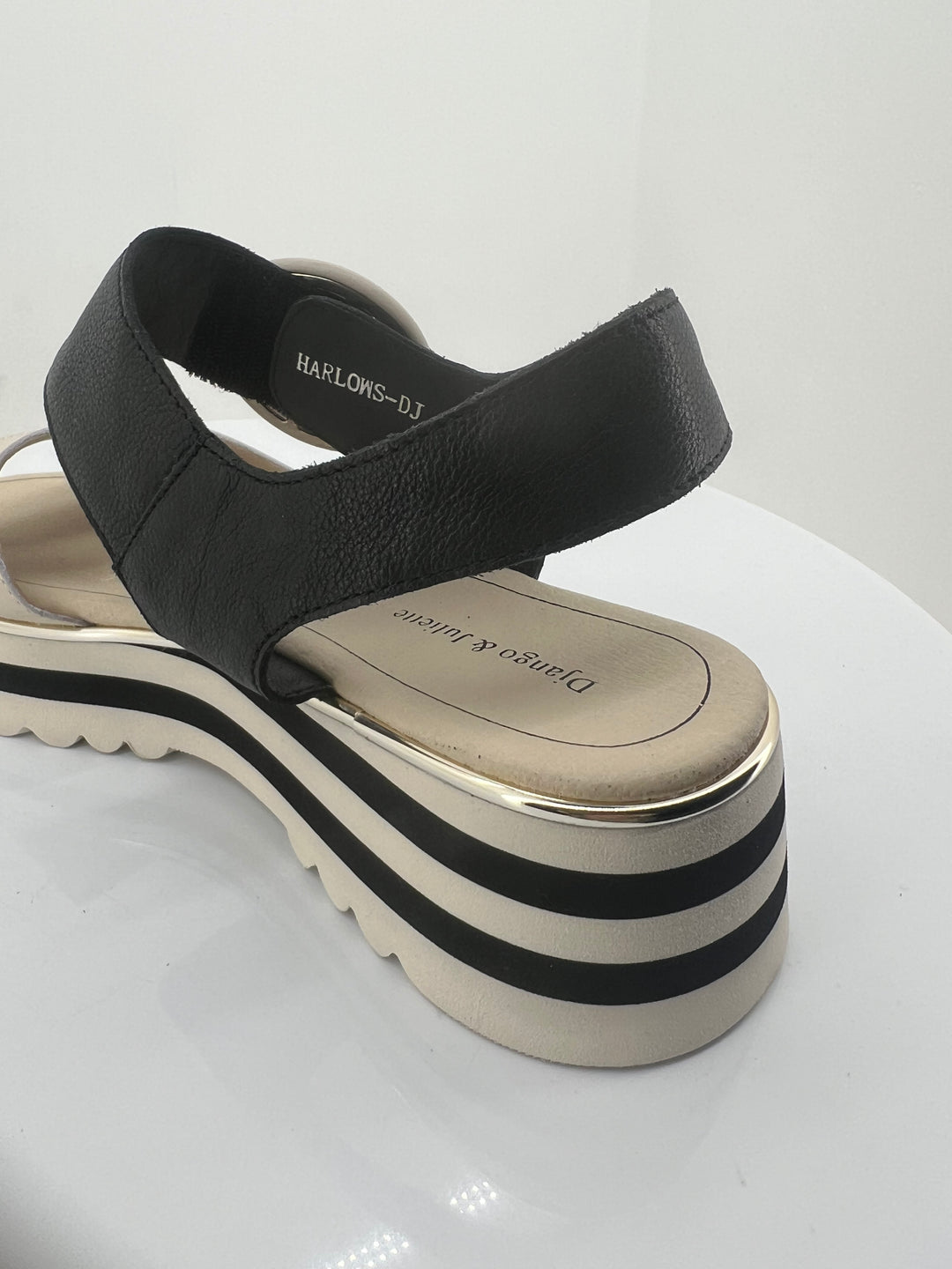 Black and white sandal with a thick sole on a light gray background