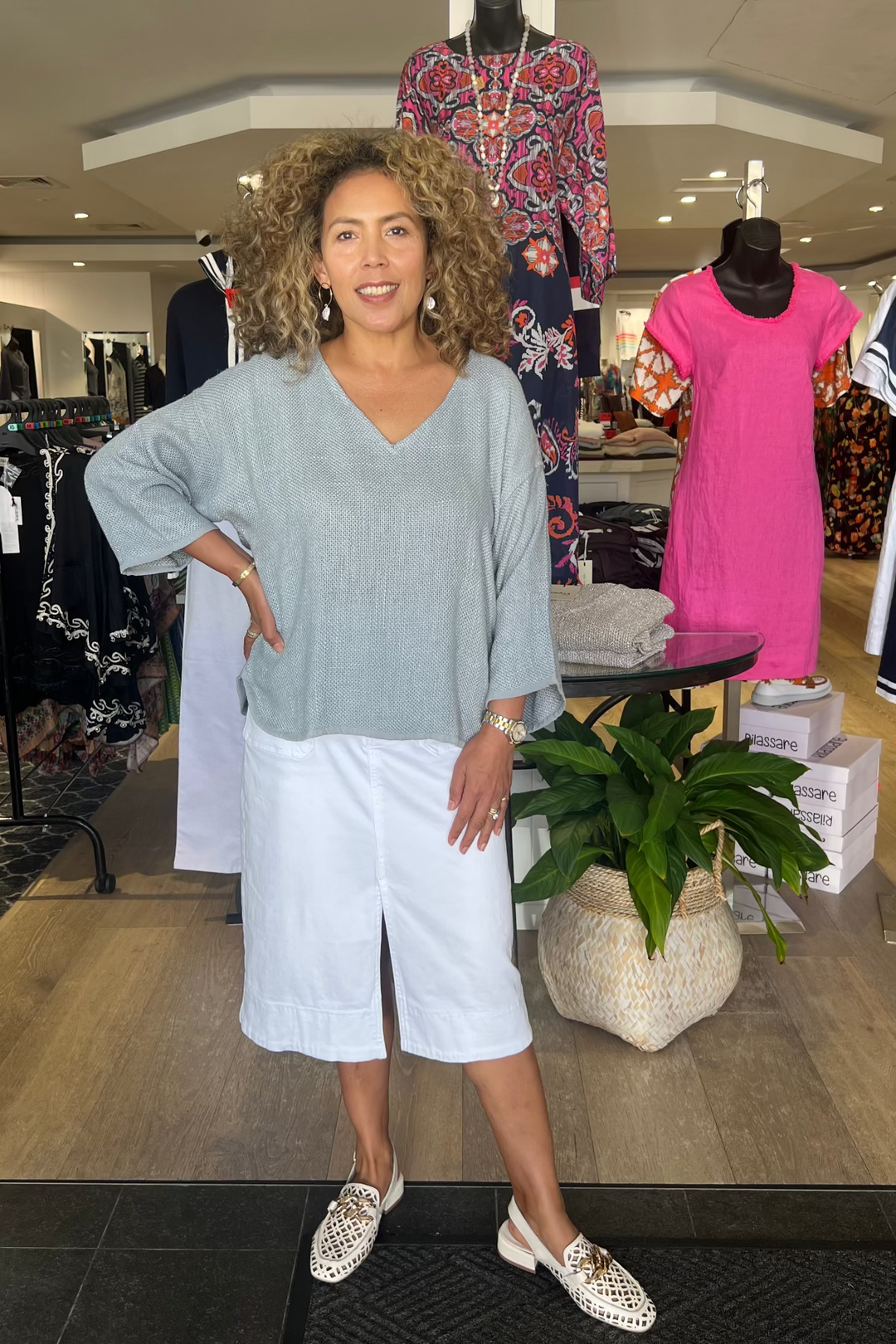 Woman standing in a clothing store with mannequins and clothing around her.