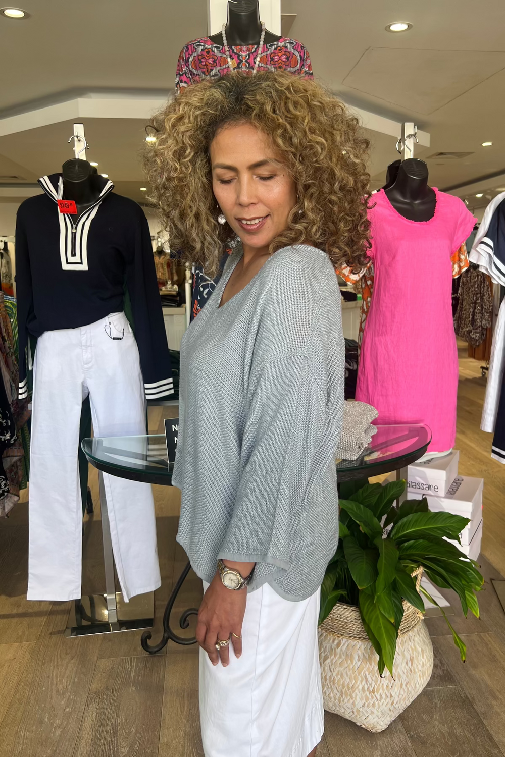 Woman standing in a clothing store with mannequins wearing various outfits.