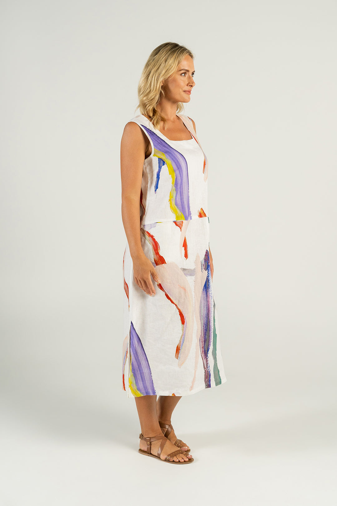 Woman wearing a white linen dress with splashes of colour front view from Pizazz Boutique Nelson Bay Dress Shop