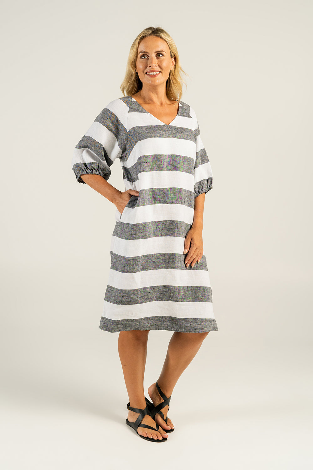 Woman wearing a grey and white striped linen dress with a V-Neck by See Saw clothing, sold and shipped from Pizazz Boutique Nelson Bay online women's clothes shops Australia