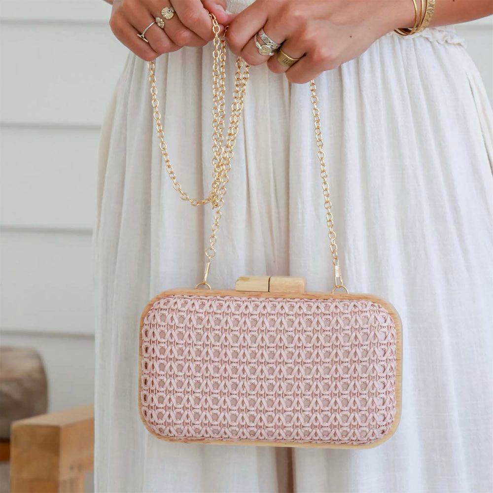 Lady holding a timber frame clutch in blush pink , with a gold chain shoulder detachable strap. Sold and shipped by Pizazz Boutique Nelson Bay, Port Stephens. 