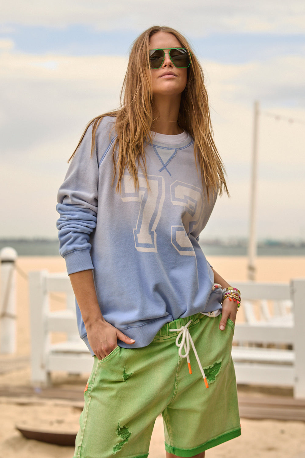 Woman wearing a blue jumper with 73 on the front an green shorts by Hammill & Co, sold and shipped from Pizazz Boutique online women's clothes shops Australia