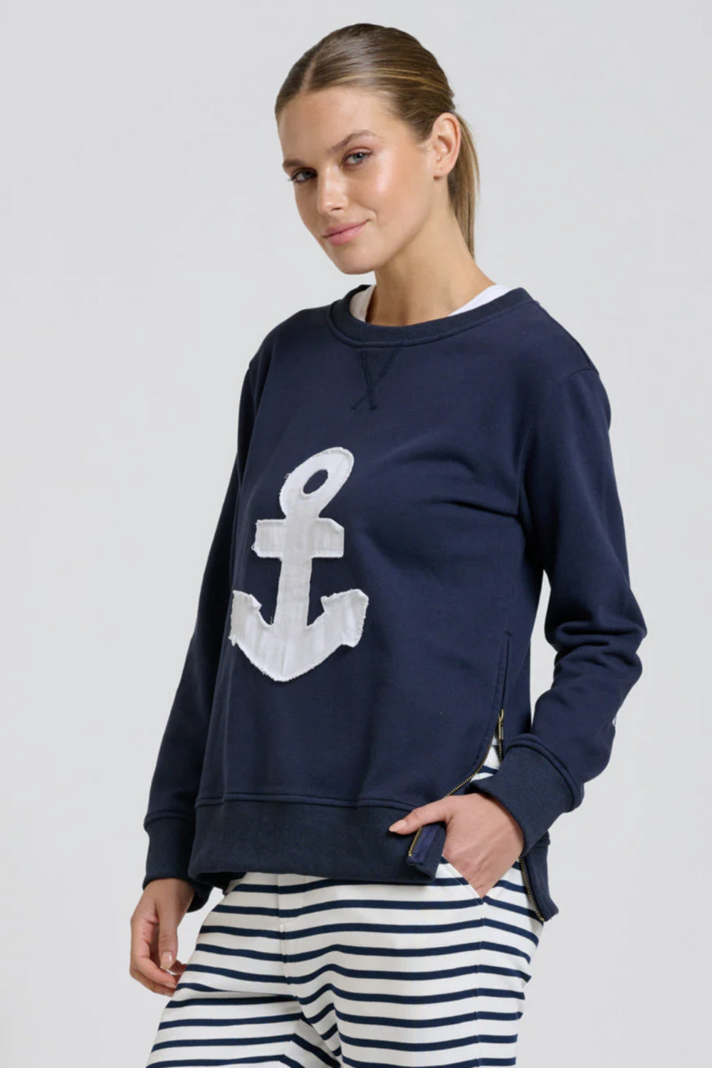 Woman wearing a navy blue sweatshirt with a white anchor design on a light gray background