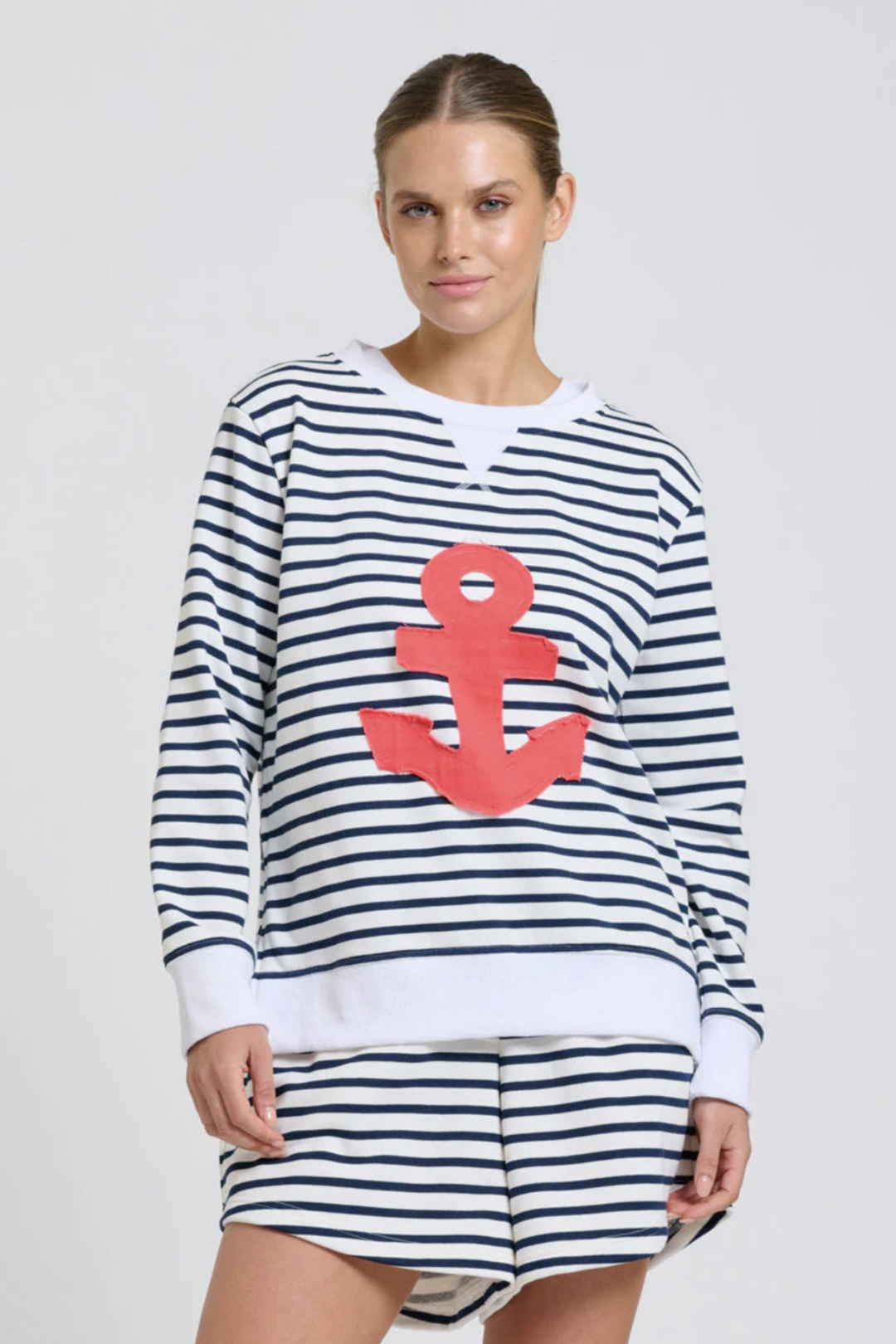 Woman wearing a striped outfit with a red anchor design on a plain background